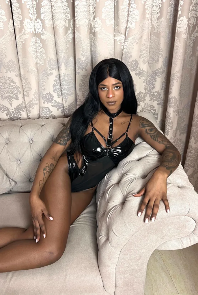 Porträt von Nina mit langen schwarzen Haaren, Tattoos und sinnlichem Blick